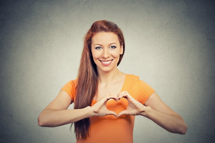 Closeup portrait smiling cheerful happy young woman making heart sign with hands isolated grey wall background. Positive human emotion expression feeling life perception attitude body language.jpeg